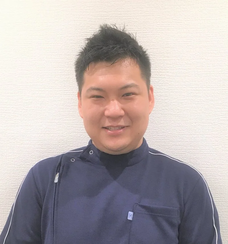 院長・関口稔。紺色の施術着を着た人物写真